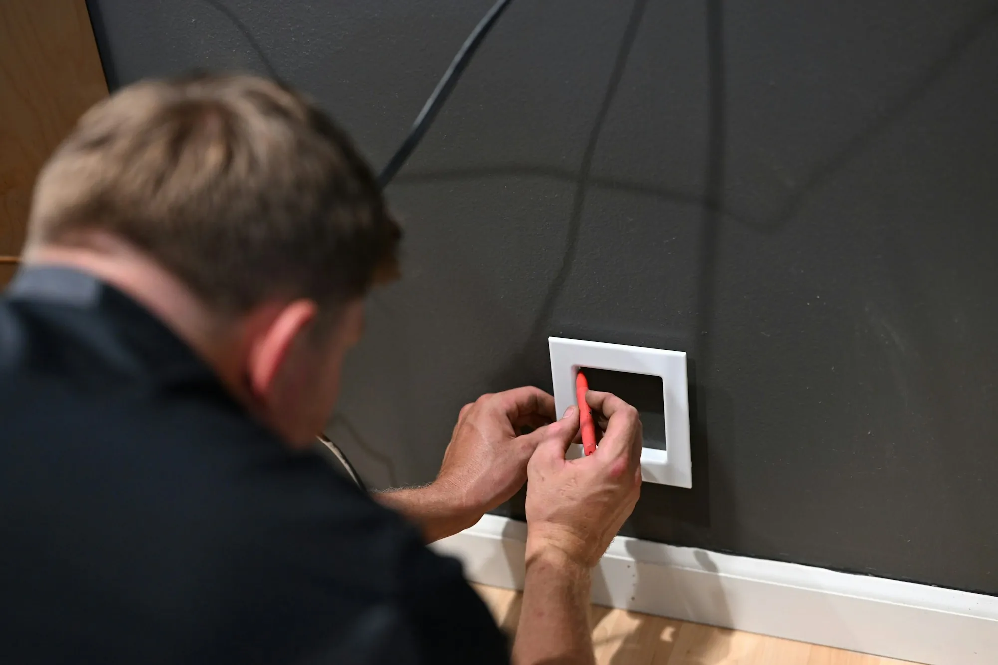 Electrician fastening a cover plate on a newly wired wall switch