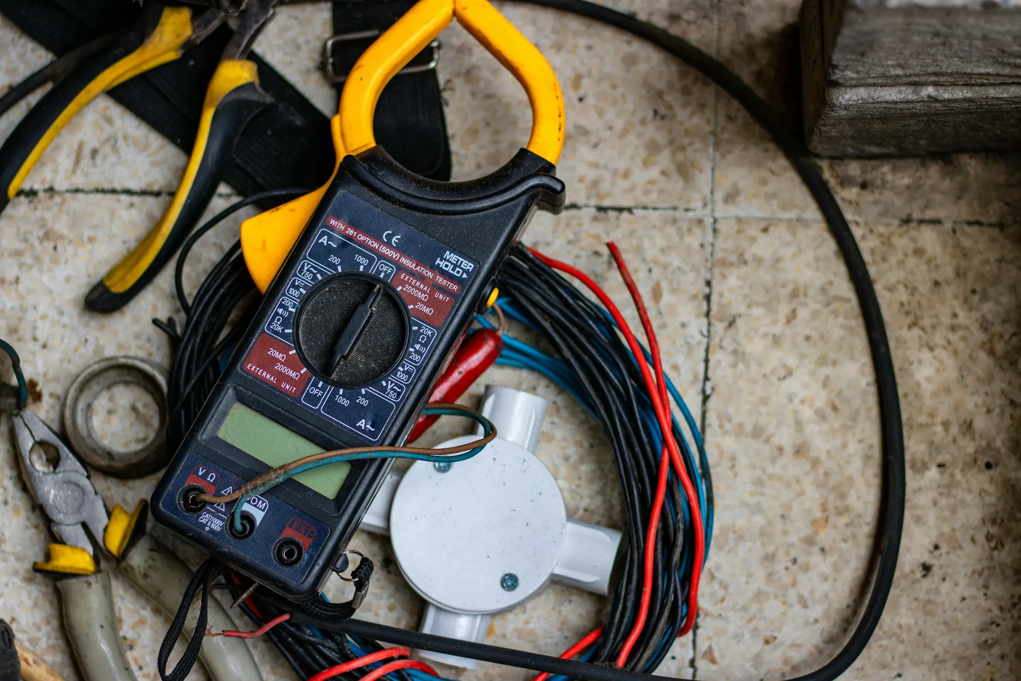 Digital multimeter and test leads laid out beside coiled electrical wire