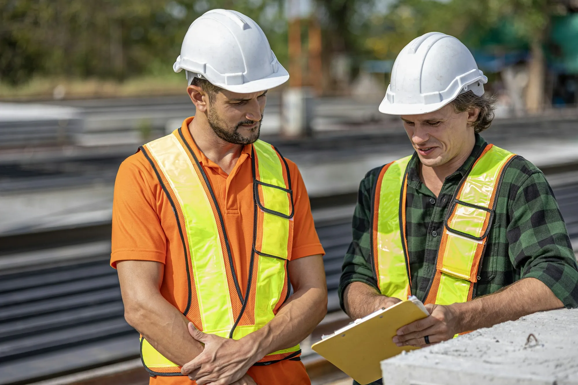 Two electricians in safety vests discussing plans on site