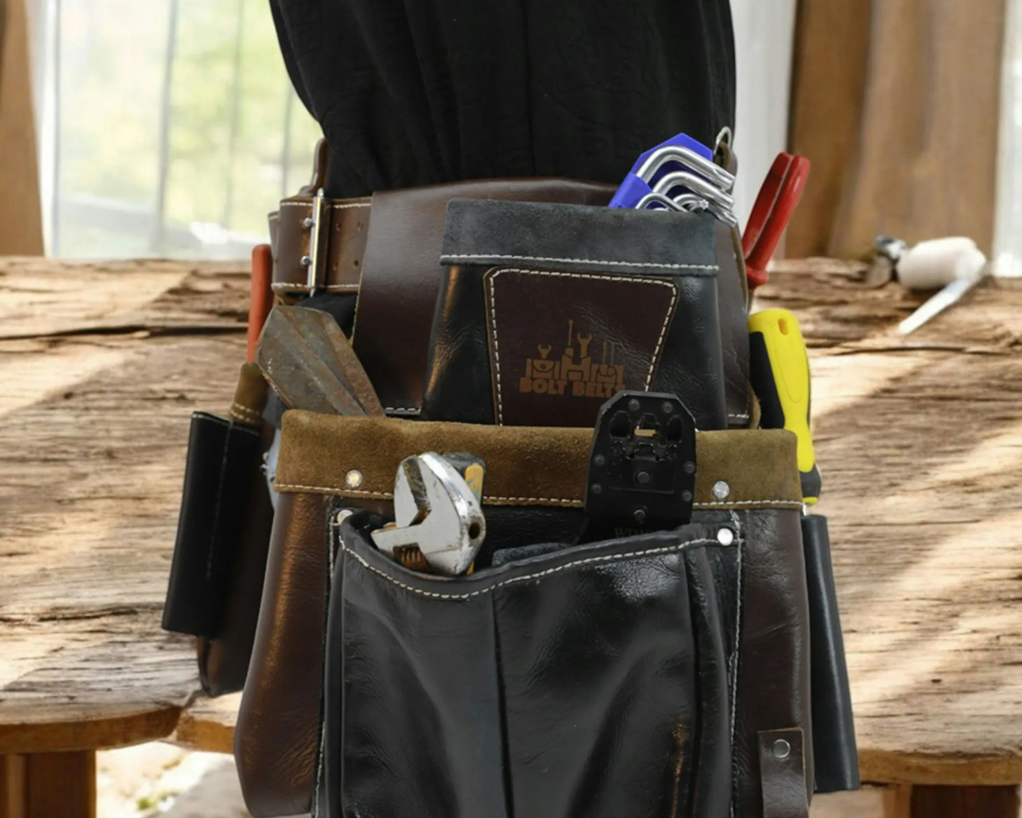 Electrician's leather tool belt with pliers and screwdrivers on a workbench